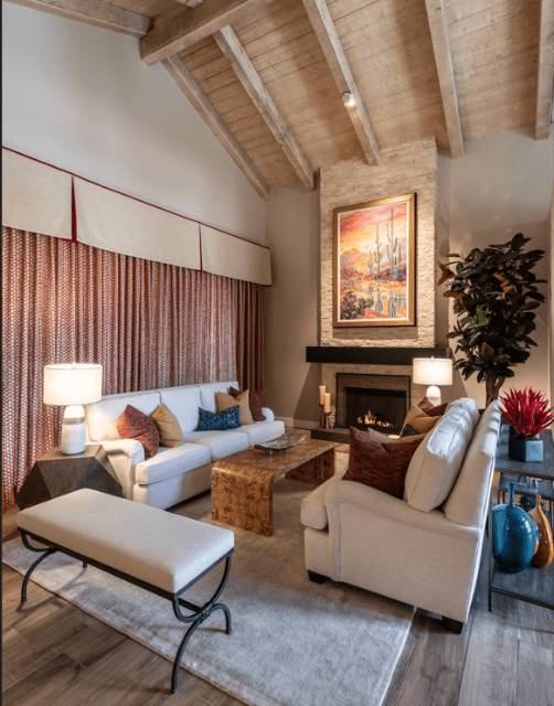 A light-filled living room with high ceilings, exposed wood and a desert artwork feature